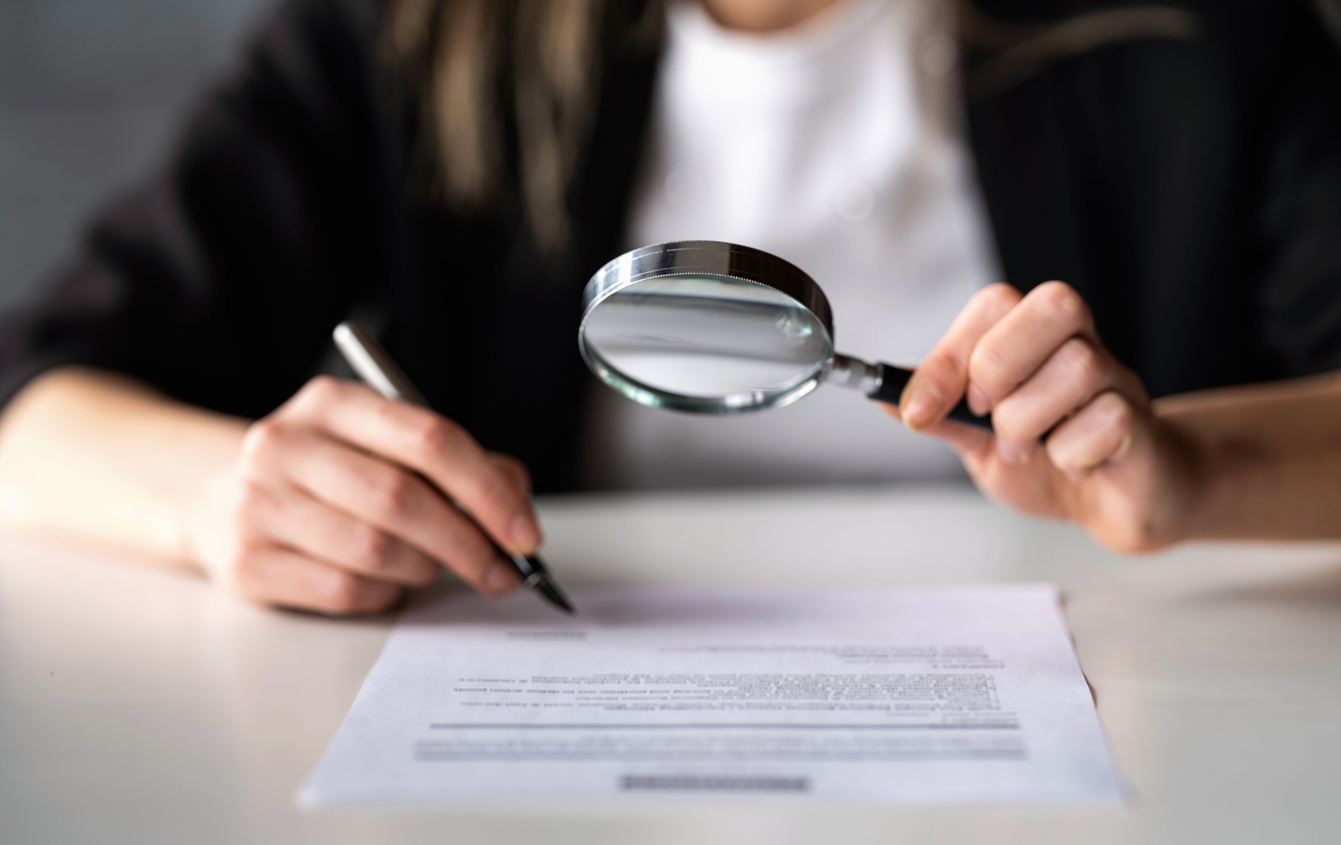 Businesswoman Reading A Legal Document Carefully Using Magnifying Glass Before Signing