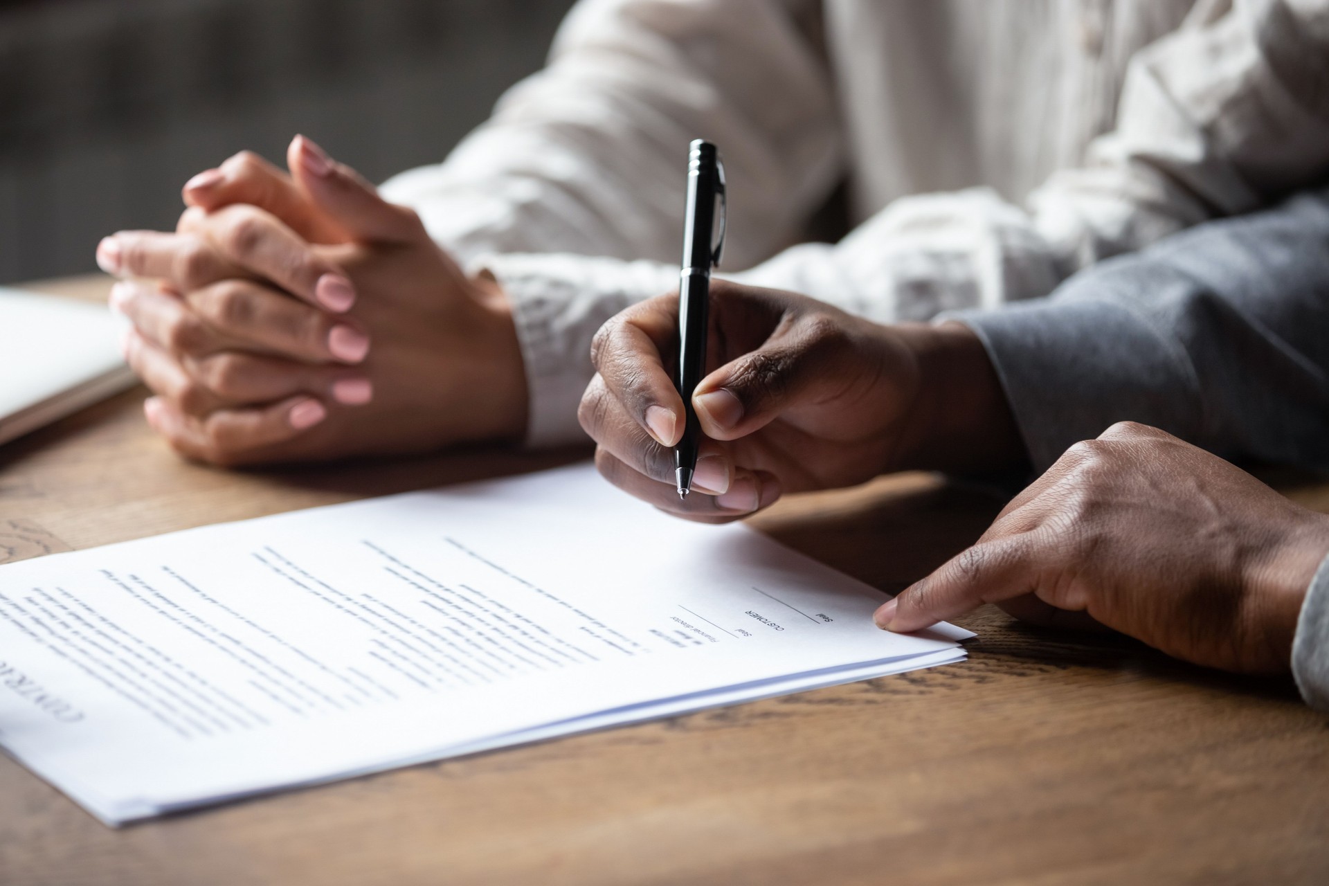 Close up of multiracial couple signing contract with Real Estate Agent